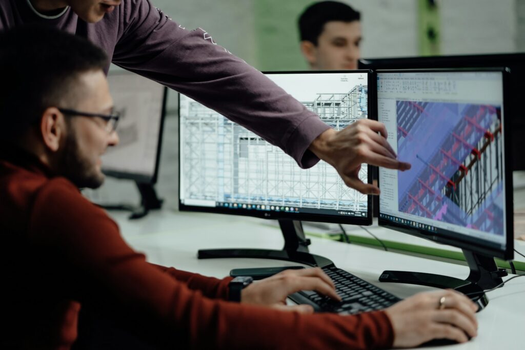 Engineers reviewing technical drawings on dual monitors