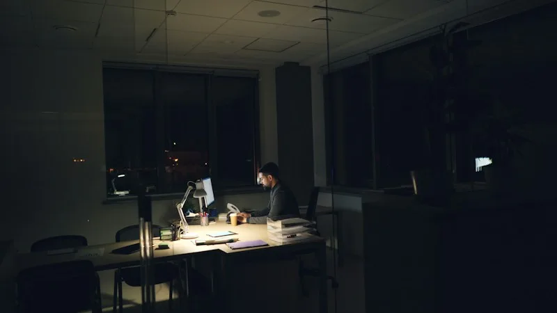 IT professional working late at a dimly lit office desk