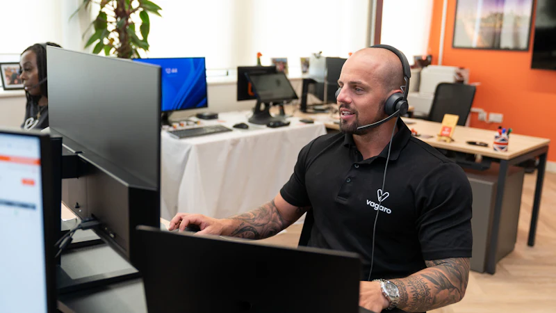 IT help desk technician wearing a headset supporting a user at a computer