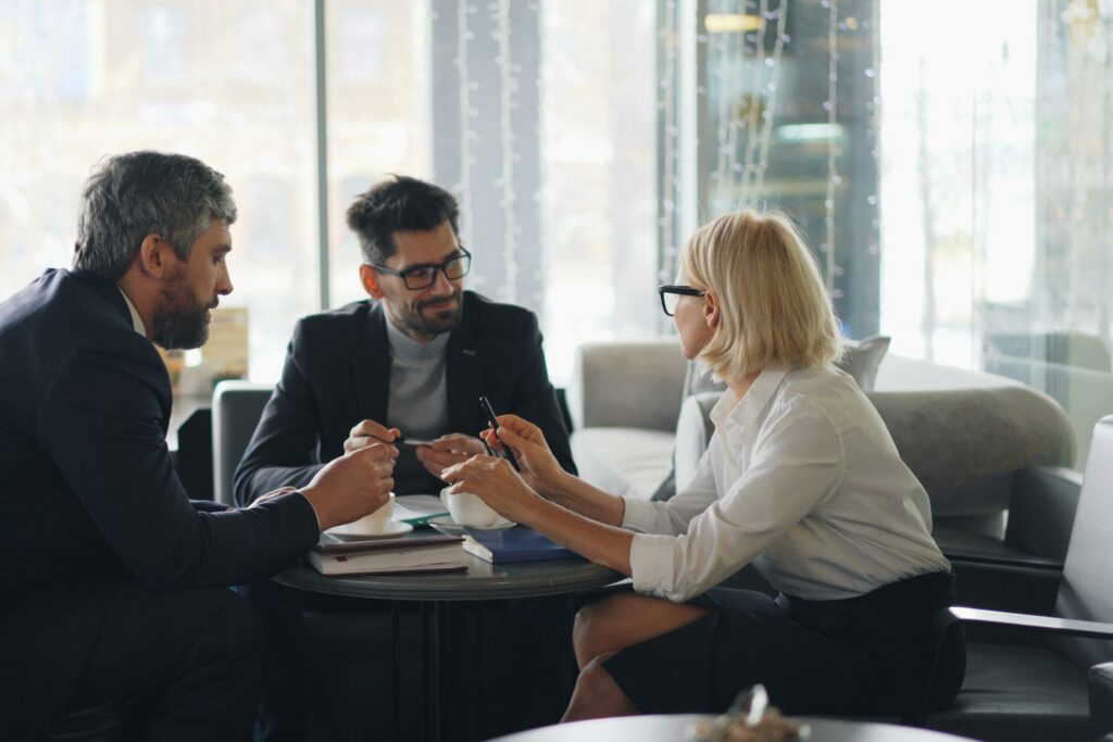 Three business professionals discussing plans around a table