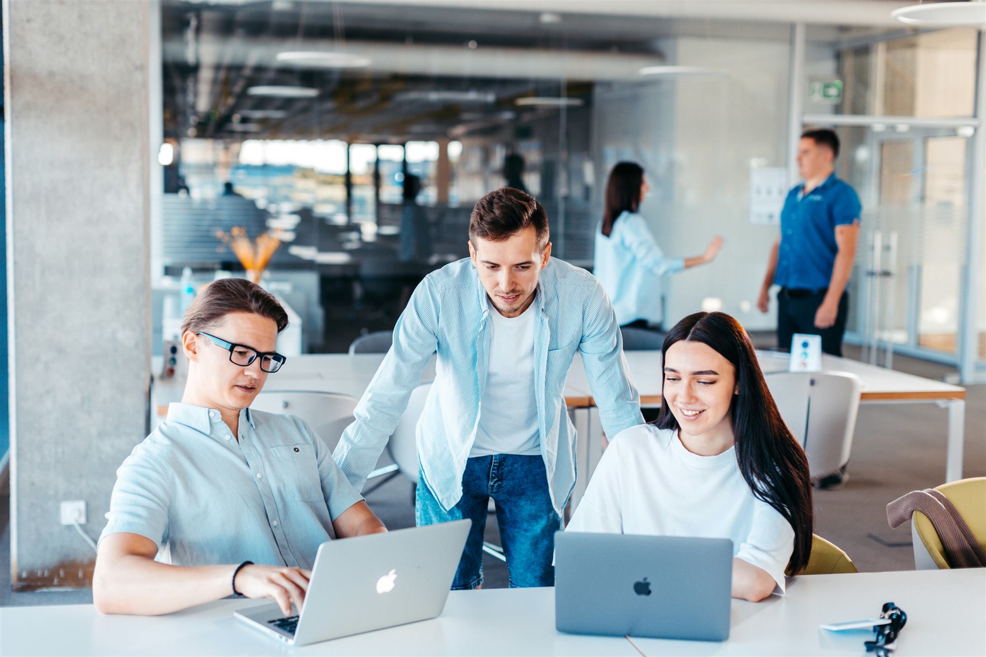 Team of IT professionals collaborating around laptops in a modern office