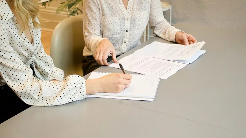 Two people reviewing and signing vendor contract documents
